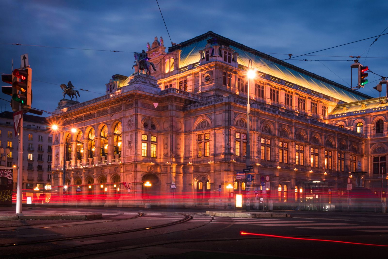 Illuminated Vienna State Opera House captured during the blue hour with light trails of passing traffic.